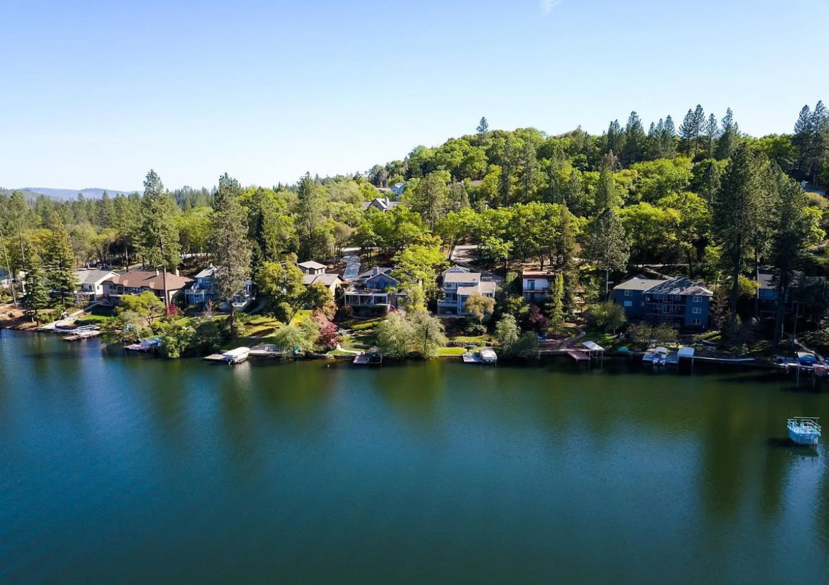 A breathtaking view of Lake Wildwood with calm waters reflecting the sky, surrounded by lush greenery and rolling hills.